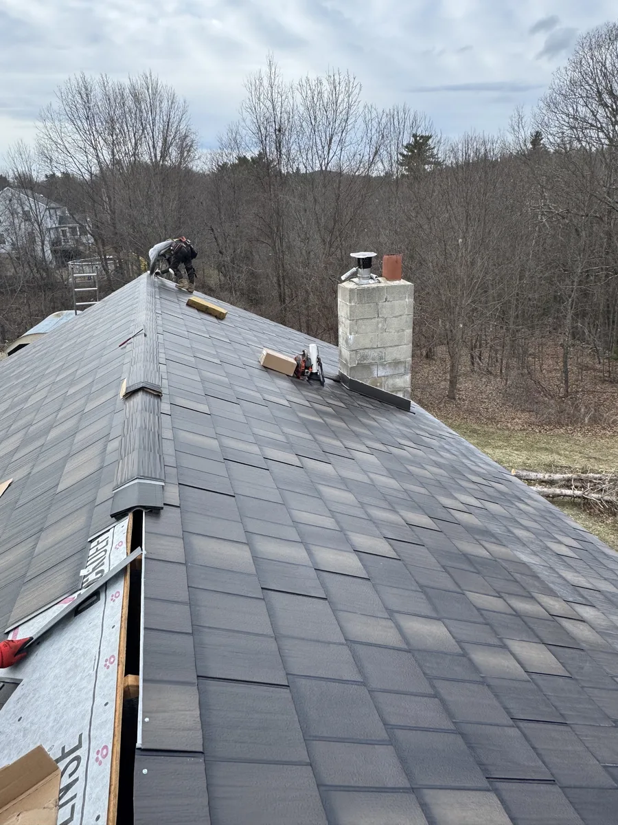 Roofer installing new flashing around a chimney during a roof replacement
