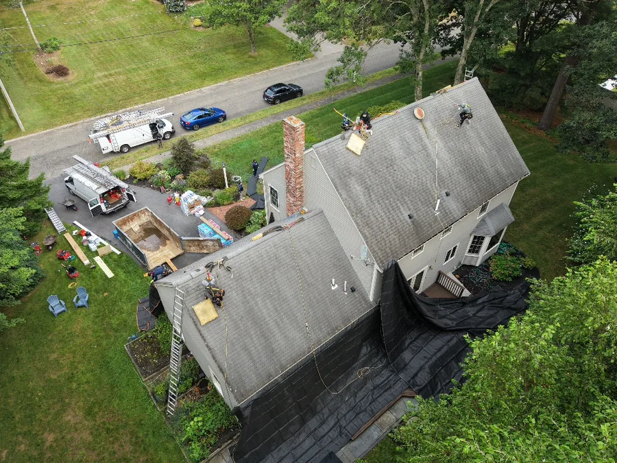 Joe's Roofing crew working on a shingle roof tear-off, aerial view