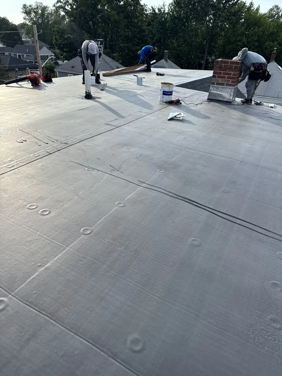 Roofing crew installing an EPDM flat roof system in Lowell, MA