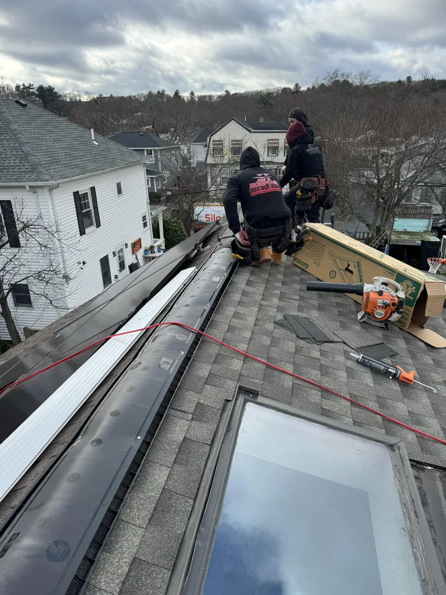 Roofers installing a new skylight on a shingle roof in Lowell, MA