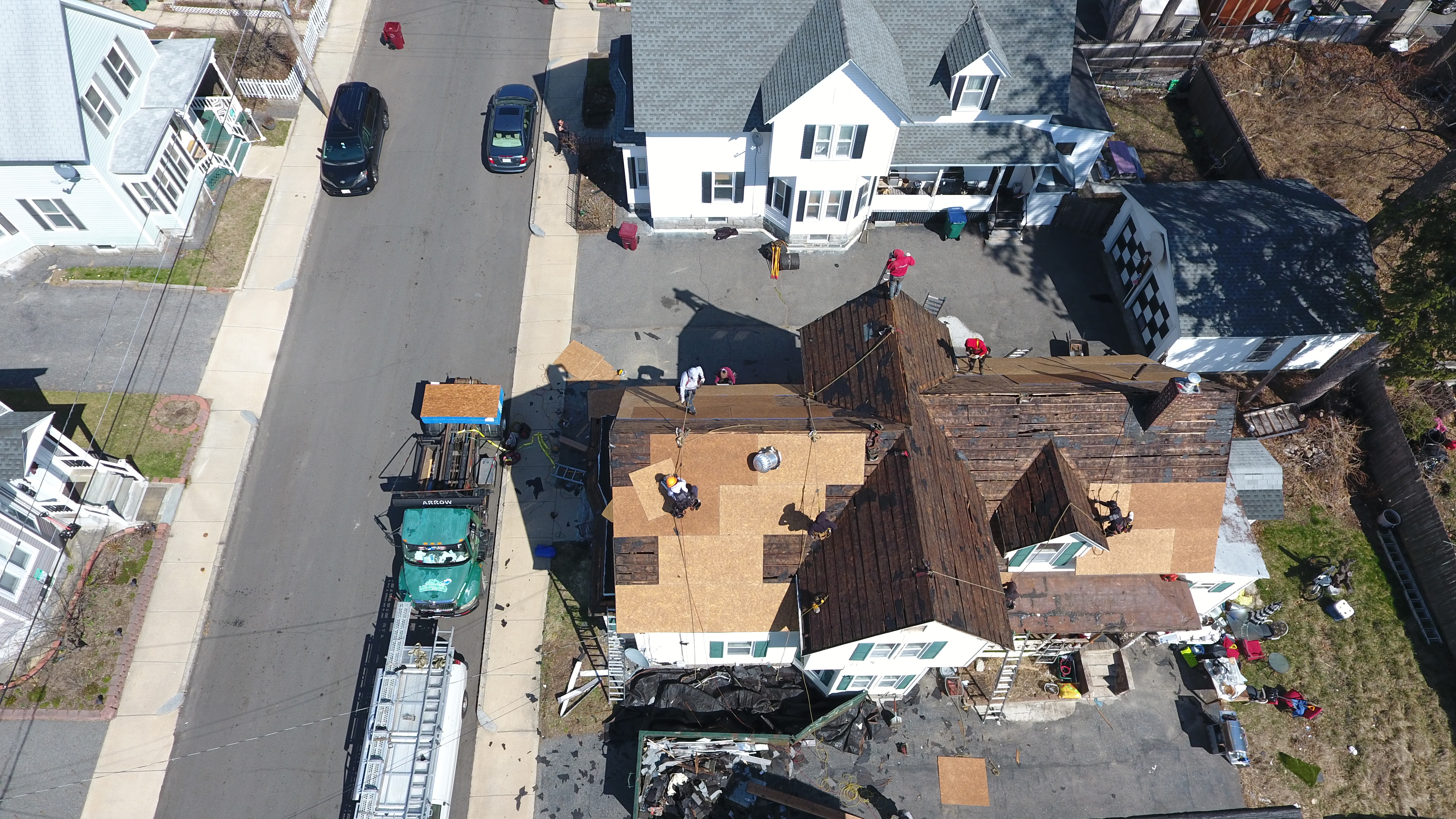 Professional roofers replacing old roof decking on single-family home in Massachusetts