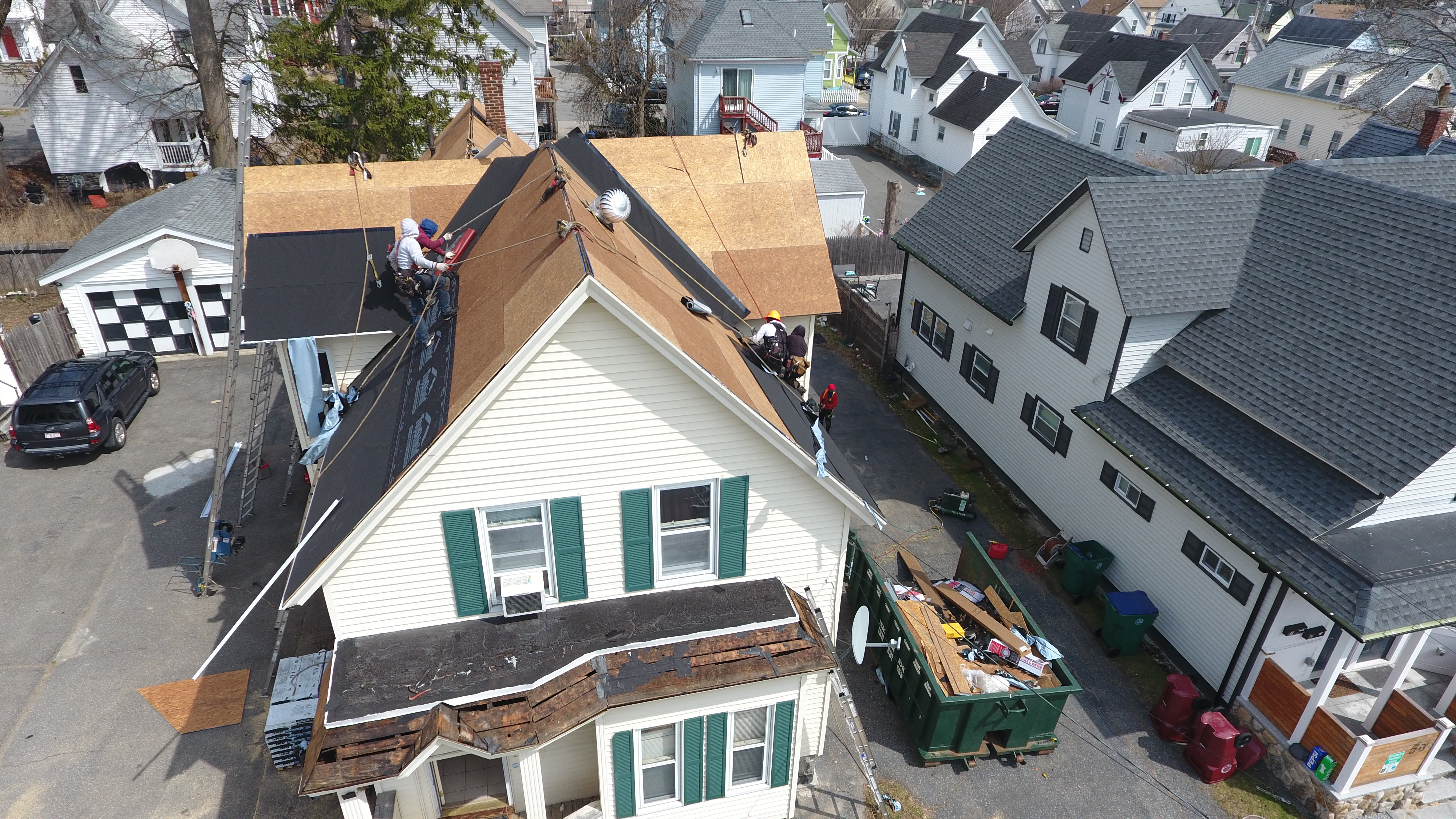 Residential roofing contractors installing three-tab asphalt shingles in Manchester NH neighborhood