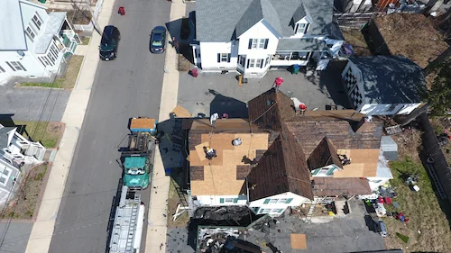 Storm damaged asphalt shingles showing missing granules and exposed underlayment in Lowell Massachusetts