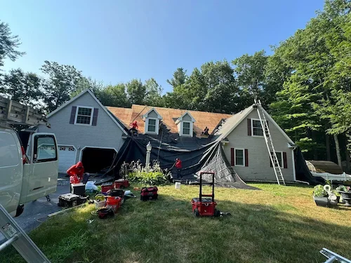 Professional roofer installing ice and water shield barrier during roof replacement in New England