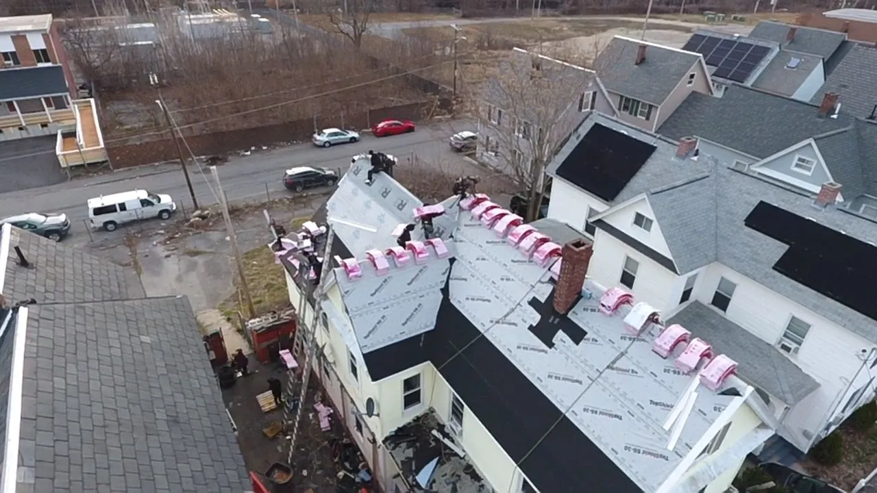 Emergency roof repair crew tarping storm-damaged roof in Manchester NH